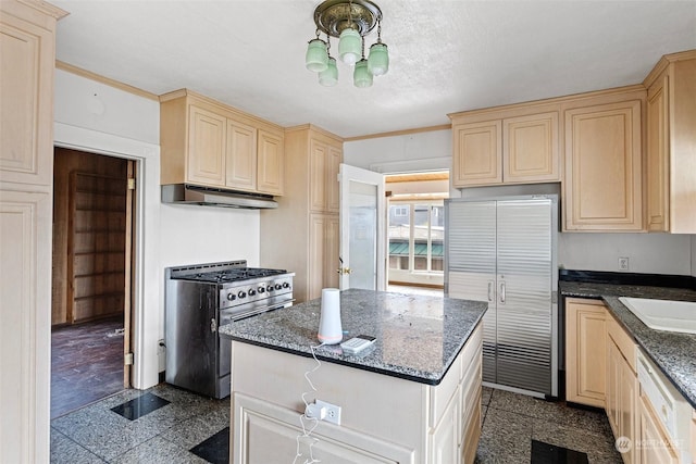 kitchen featuring sink, appliances with stainless steel finishes, an inviting chandelier, a center island, and dark stone counters