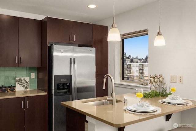 kitchen featuring stainless steel refrigerator with ice dispenser, decorative light fixtures, sink, and backsplash