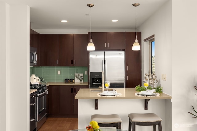 kitchen with appliances with stainless steel finishes, a kitchen bar, and decorative light fixtures