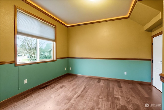 unfurnished room with crown molding, lofted ceiling, and light wood-type flooring