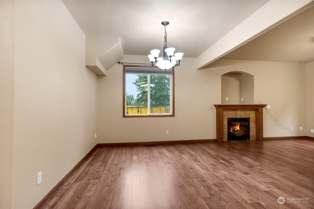 unfurnished living room featuring a fireplace, a chandelier, and wood-type flooring