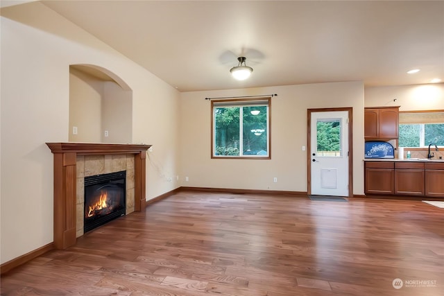 unfurnished living room with hardwood / wood-style flooring, sink, a wealth of natural light, and a fireplace