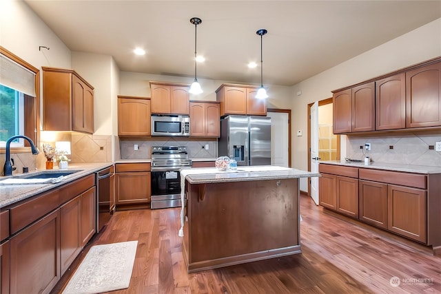 kitchen featuring appliances with stainless steel finishes, decorative light fixtures, tasteful backsplash, sink, and dark wood-type flooring