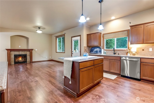 kitchen featuring pendant lighting, a tile fireplace, dishwasher, tasteful backsplash, and light hardwood / wood-style floors