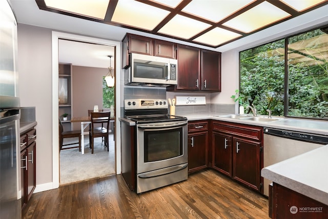 kitchen featuring stainless steel appliances, dark hardwood / wood-style flooring, sink, decorative light fixtures, and tasteful backsplash