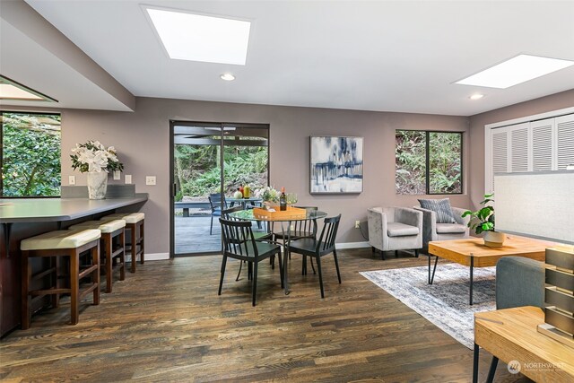 dining space with a skylight, dark hardwood / wood-style flooring, and plenty of natural light