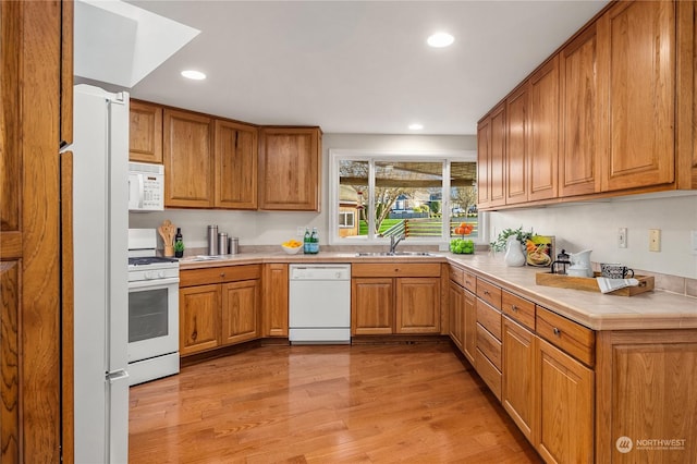 kitchen featuring sink, white appliances, and light wood-type flooring