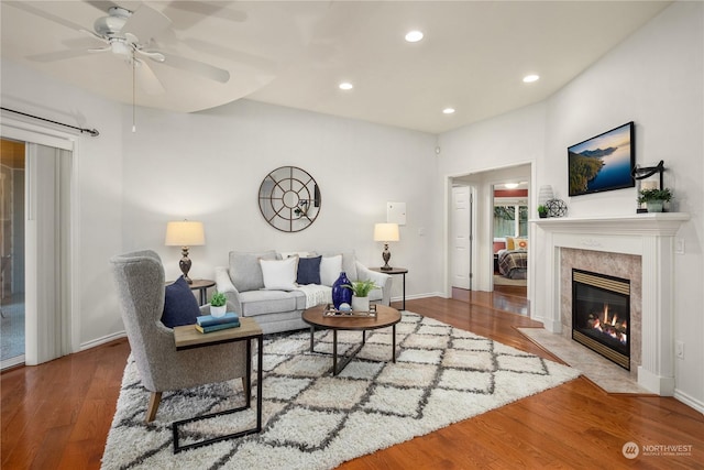 living room with a premium fireplace, hardwood / wood-style floors, and ceiling fan