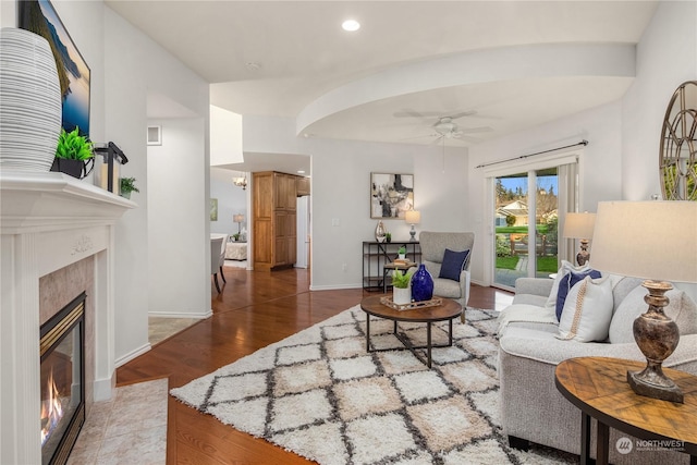 living room featuring ceiling fan, hardwood / wood-style floors, and a fireplace