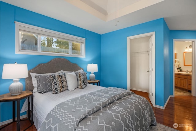 bedroom with sink, a walk in closet, ensuite bath, dark hardwood / wood-style floors, and a closet