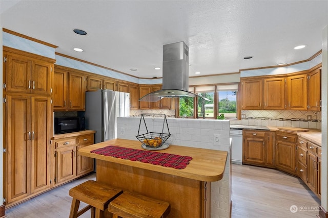 kitchen with white dishwasher, stainless steel fridge, a kitchen island, ornamental molding, and island range hood