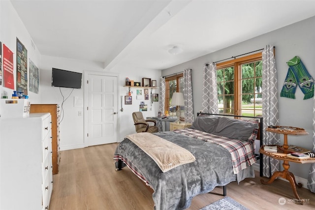 bedroom featuring beamed ceiling and light hardwood / wood-style floors