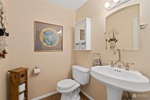 bathroom featuring toilet, tile patterned floors, and sink