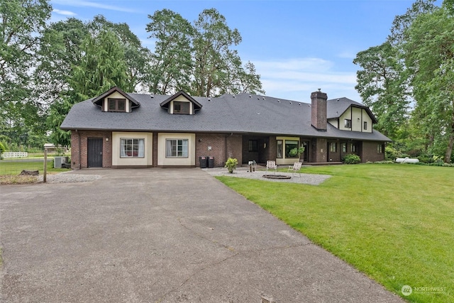 view of front of house with a fire pit, central AC, and a front lawn