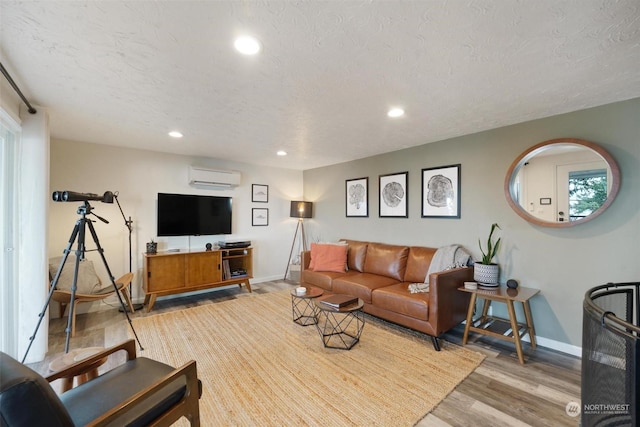 living room with a textured ceiling, light wood-type flooring, and a wall mounted AC