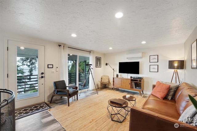 living room featuring hardwood / wood-style flooring, an AC wall unit, and a textured ceiling