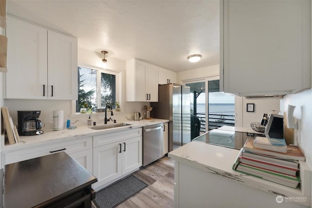 kitchen featuring a water view, sink, light hardwood / wood-style floors, white cabinetry, and stainless steel appliances