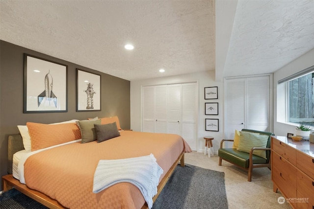 bedroom with beam ceiling, light colored carpet, and a textured ceiling