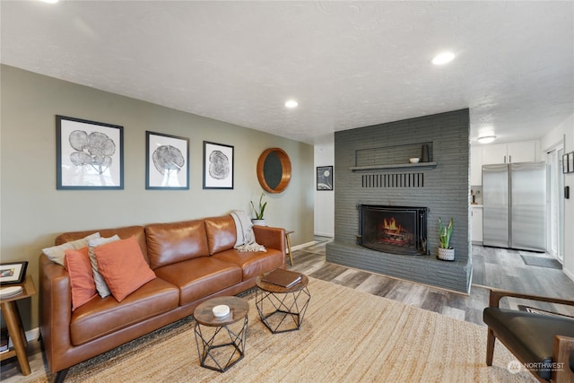 living room with a textured ceiling, wood-type flooring, and a fireplace