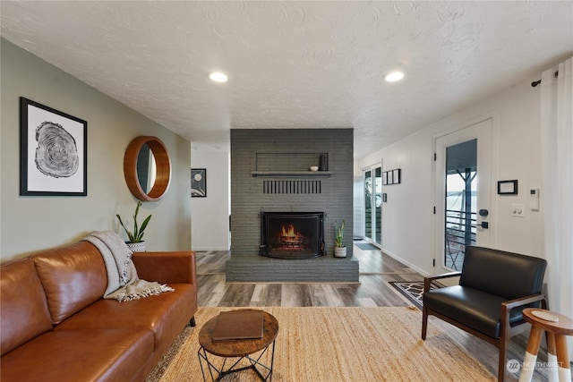 living room with a fireplace, wood-type flooring, and a textured ceiling