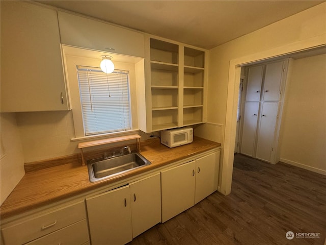 kitchen featuring dark hardwood / wood-style floors, white cabinetry, and sink