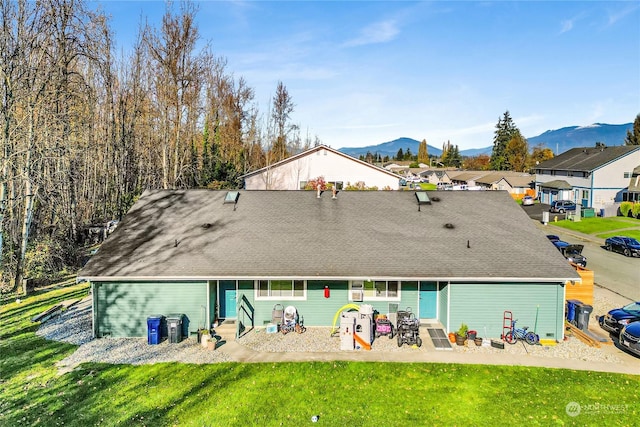 rear view of property featuring a mountain view, a yard, and a patio