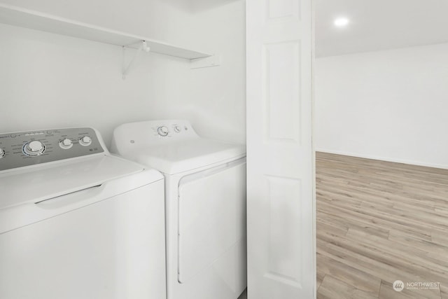 clothes washing area featuring independent washer and dryer and light hardwood / wood-style floors