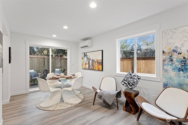 dining room with a wealth of natural light, a wall mounted air conditioner, and light hardwood / wood-style floors