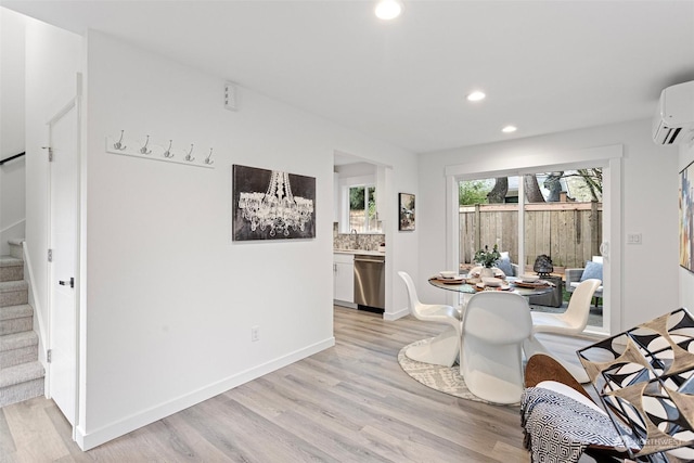 dining space featuring sink, light hardwood / wood-style flooring, and a wall unit AC