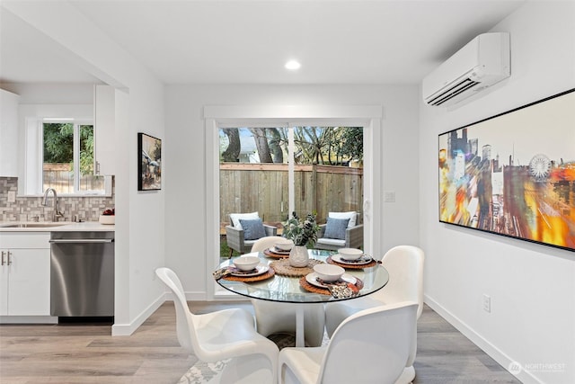 dining room featuring sink, a wall unit AC, and light hardwood / wood-style floors