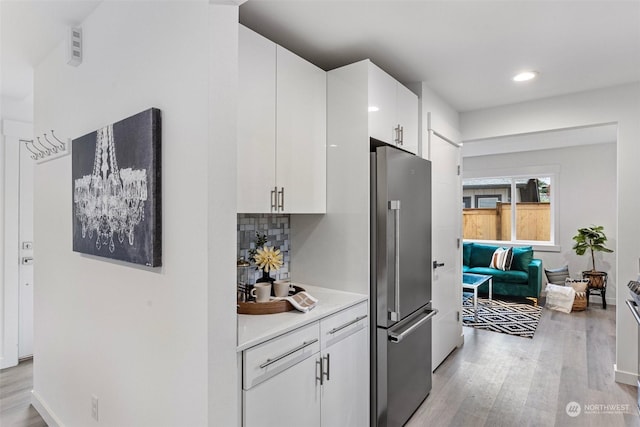 kitchen featuring white cabinetry, high quality fridge, tasteful backsplash, and light wood-type flooring