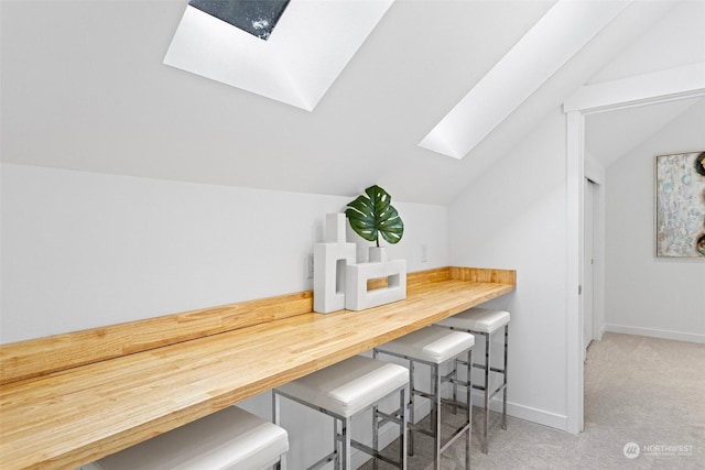 dining space featuring carpet floors and lofted ceiling with skylight