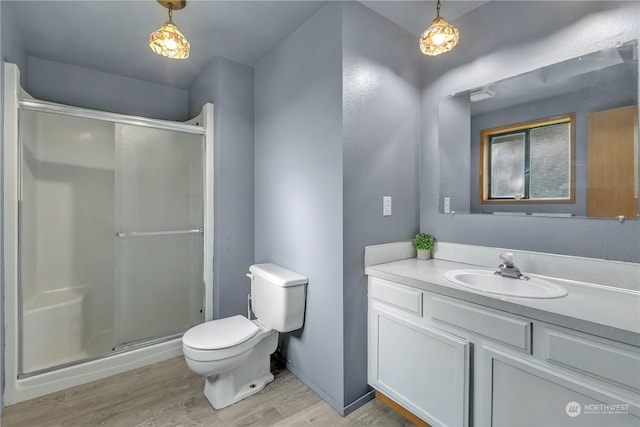 bathroom with vanity, hardwood / wood-style flooring, toilet, and a shower with door