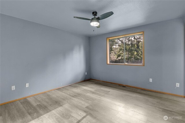 empty room with ceiling fan and light hardwood / wood-style flooring