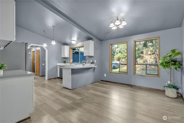 kitchen with kitchen peninsula, appliances with stainless steel finishes, decorative light fixtures, white cabinetry, and lofted ceiling