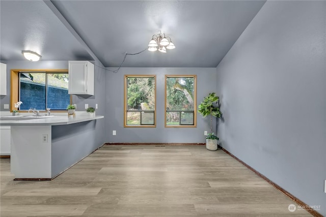 kitchen with white cabinetry, plenty of natural light, a chandelier, and light hardwood / wood-style flooring