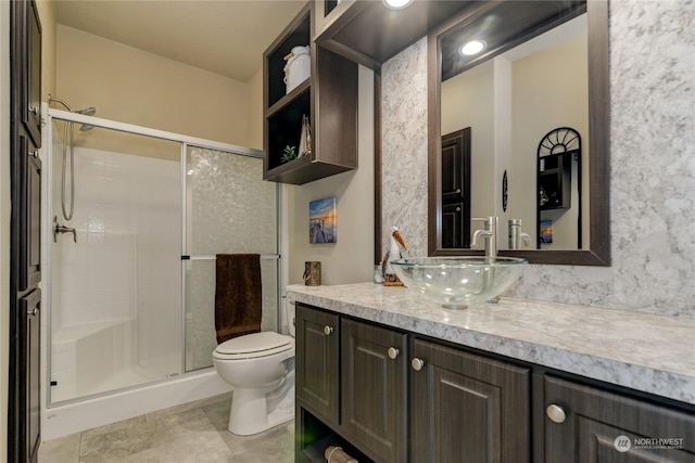 bathroom featuring a shower with door, vanity, and toilet