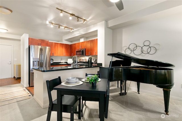 kitchen with kitchen peninsula, light carpet, stainless steel appliances, ceiling fan, and sink