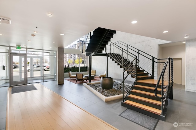 stairway featuring french doors, hardwood / wood-style flooring, and a wall of windows