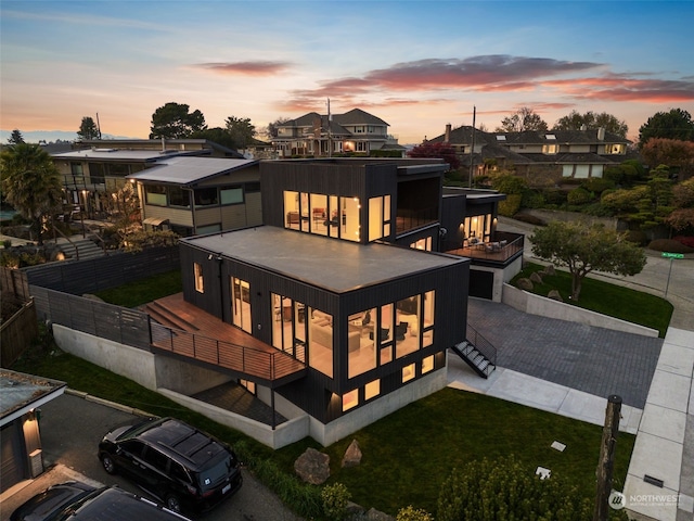 back house at dusk with a yard and a balcony