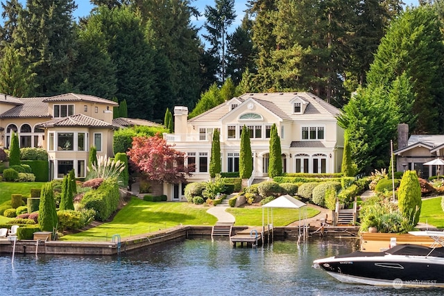 rear view of house featuring a water view and a lawn