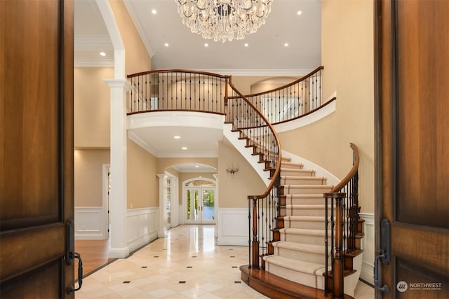 tiled entrance foyer featuring a notable chandelier, ornamental molding, and french doors