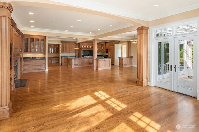 unfurnished living room with a chandelier, light hardwood / wood-style floors, ornamental molding, and french doors