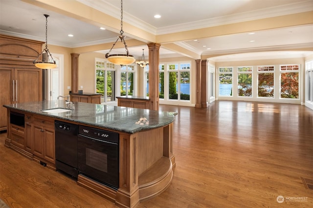 kitchen featuring black appliances, pendant lighting, sink, and an island with sink