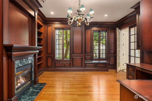 office space with a chandelier, crown molding, wooden walls, and a high end fireplace