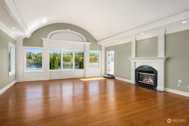 unfurnished living room featuring wood-type flooring, vaulted ceiling, ornamental molding, and a premium fireplace