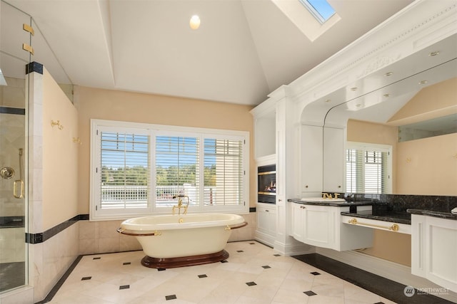 bathroom with tile patterned floors, vanity, lofted ceiling with skylight, and shower with separate bathtub