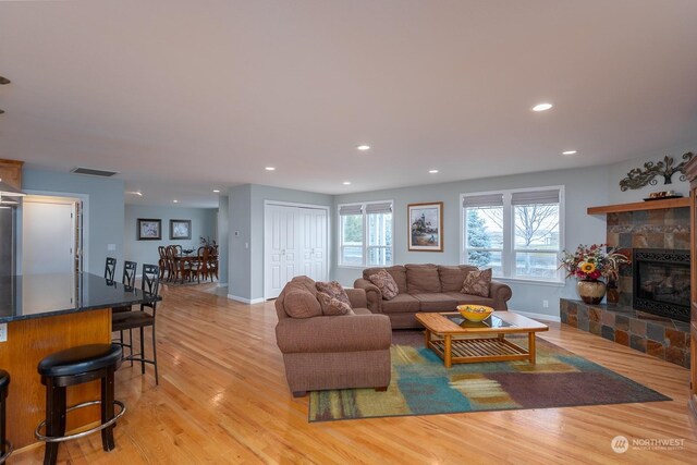 living room featuring light wood-type flooring and a stone fireplace