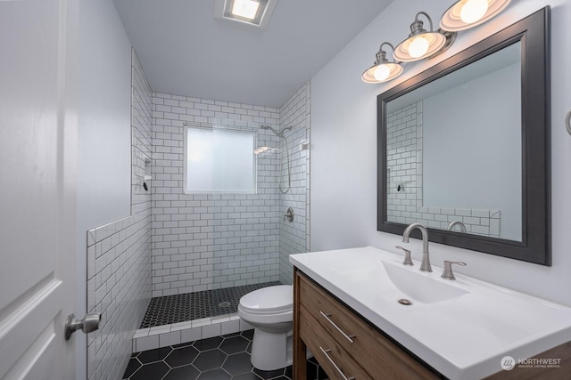 bathroom with tile patterned flooring, a tile shower, vanity, and toilet