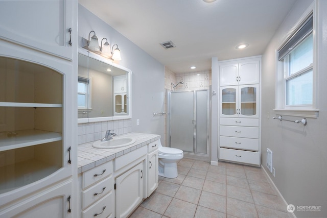 bathroom featuring backsplash, vanity, tile patterned flooring, toilet, and a shower with shower door